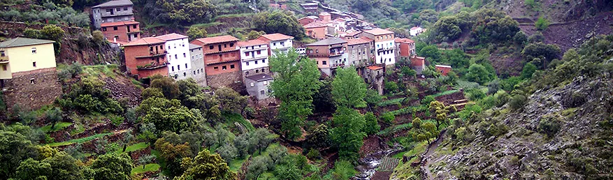 Alquería de El Gasco, en Nuñomoral, con sus casas escalonadas en la ladera sobre el arroyo